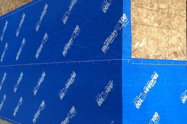 Blue construction sheathing panels installed on an exterior wall of a building under construction.