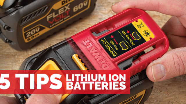 Close-up of a person holding a red and black DeWalt lithium ion battery with product details visible.
