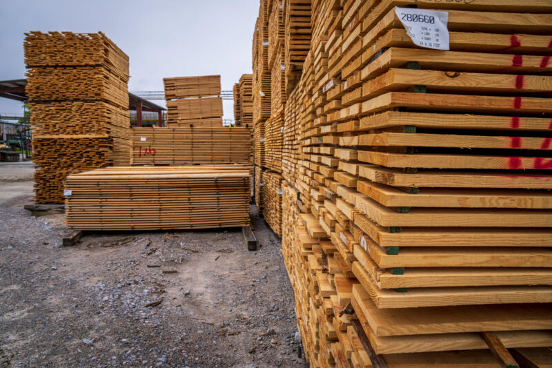 Stacks of wooden planks neatly arranged outdoors in a lumberyard.
