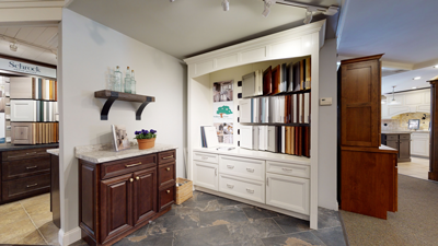 kitchen showroom with wooden cabinets, countertop, and shelving displaying various cabinet door samples and decor items