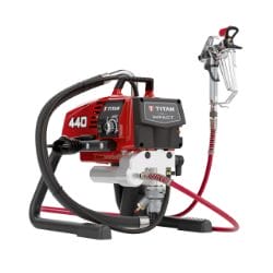 Airless paint sprayer with red housing, black hose, and attached spray gun.