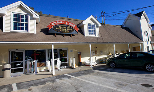 A rustic liquor store with a wooden sign and a car parked in front under a clear blue sky.