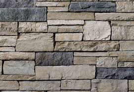 Stacked stone wall with various shades of gray and beige rectangular stones.