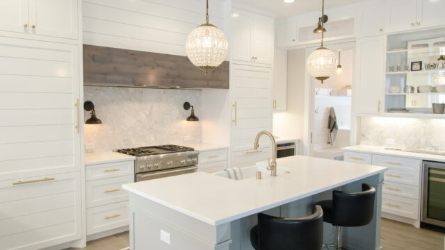 Modern kitchen with white cabinetry, large island, pendant lighting, and stainless steel appliances.