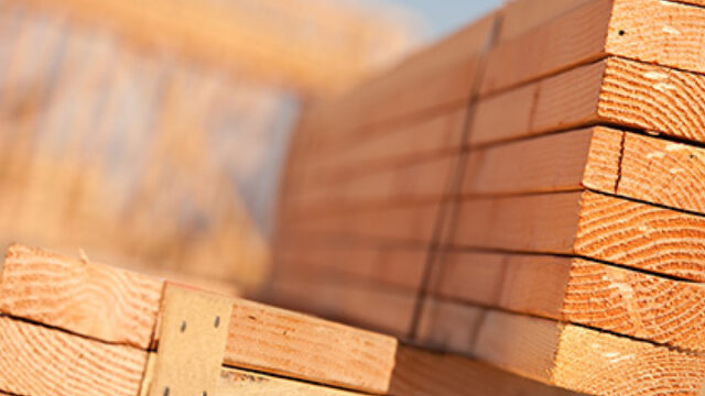 Stack of wooden planks arranged in a construction site with blurred background.