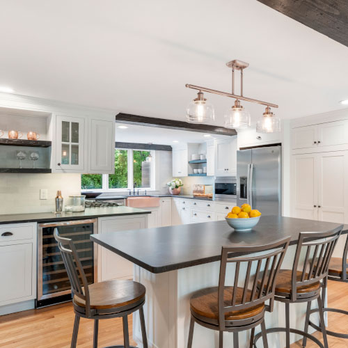 Modern kitchen interior with island, bar stools, and stainless steel appliances.