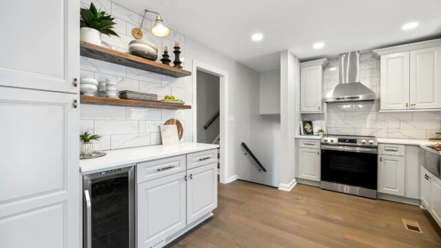 A kitchen uses open wood shelving to store ceramic dinnerware, a plant, and decor items.