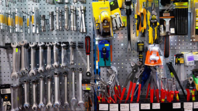 Tools and hardware neatly organized on a display wall in a store, including wrenches, pliers, and screwdrivers.