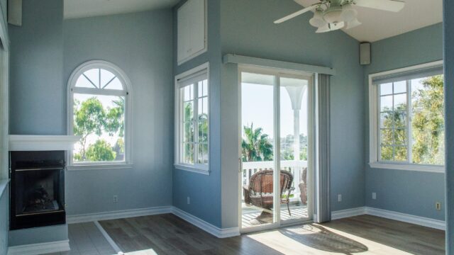 A modern interior living room has blue walls and large windows.