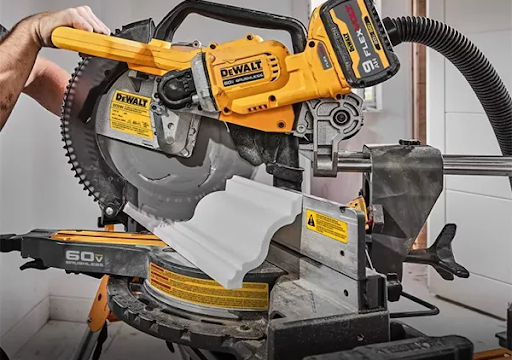 This image depicts a miter saw being used to cut a piece of wood.