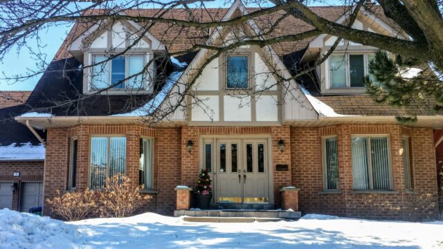 This image depicts a house during the winter months. Snow is on the ground and scattered on the roof.