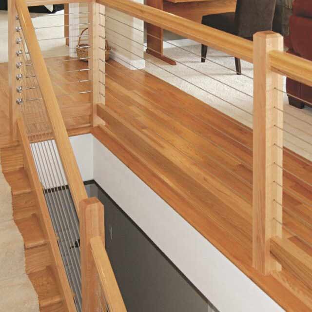 Stylish wooden staircase with cable railing, light wood floors, and carpeted area in modern indoor setting.