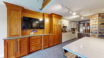 Modern kitchen showroom with wooden cabinets, countertop displays, and various kitchen design samples.