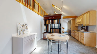 showroom with cabinetry displays, a round table, and samples on a white cabinet under angled skylights