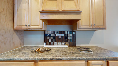 Kitchen countertop with wood cabinets, granite samples, and backsplash design displayed for renovation inspiration.