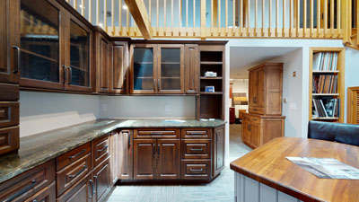 Spacious kitchen with dark wooden cabinets, granite countertops, and a view of an open living area in the background.