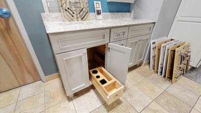 kitchen cabinet open with pull-out wooden drawer featuring storage compartments on tiled floor near countertop and wall samples