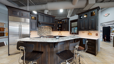 modern kitchen showroom with dark wood cabinets large island granite countertop stainless steel appliances bar stools