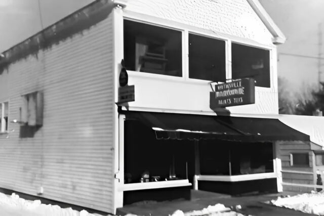 Historic two-story building with signage for The Old-Country Store y Skip's Toys, covered in snow.