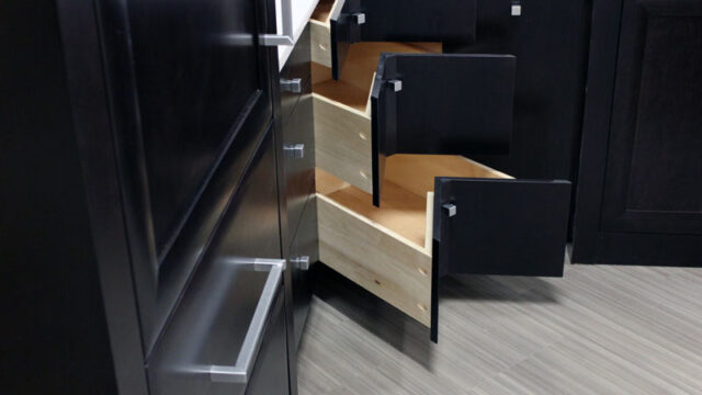 Black corner kitchen cabinets with unique angled drawers open to show interior storage space.
