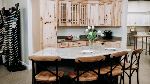 Modern kitchen with wooden cabinets, marble island, bar stools, and a vase of tulips.
