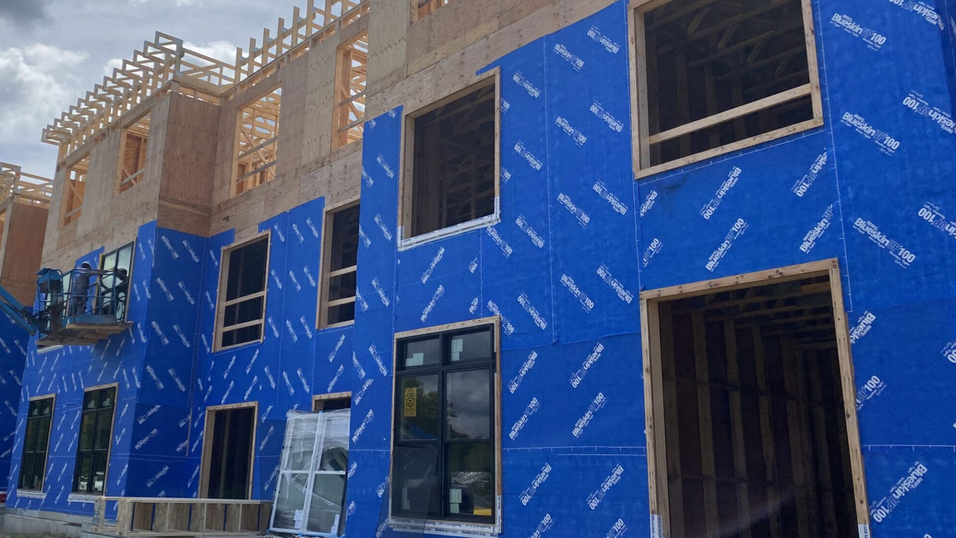 Construction site with partially built wooden structure and blue insulation panels on exterior walls.