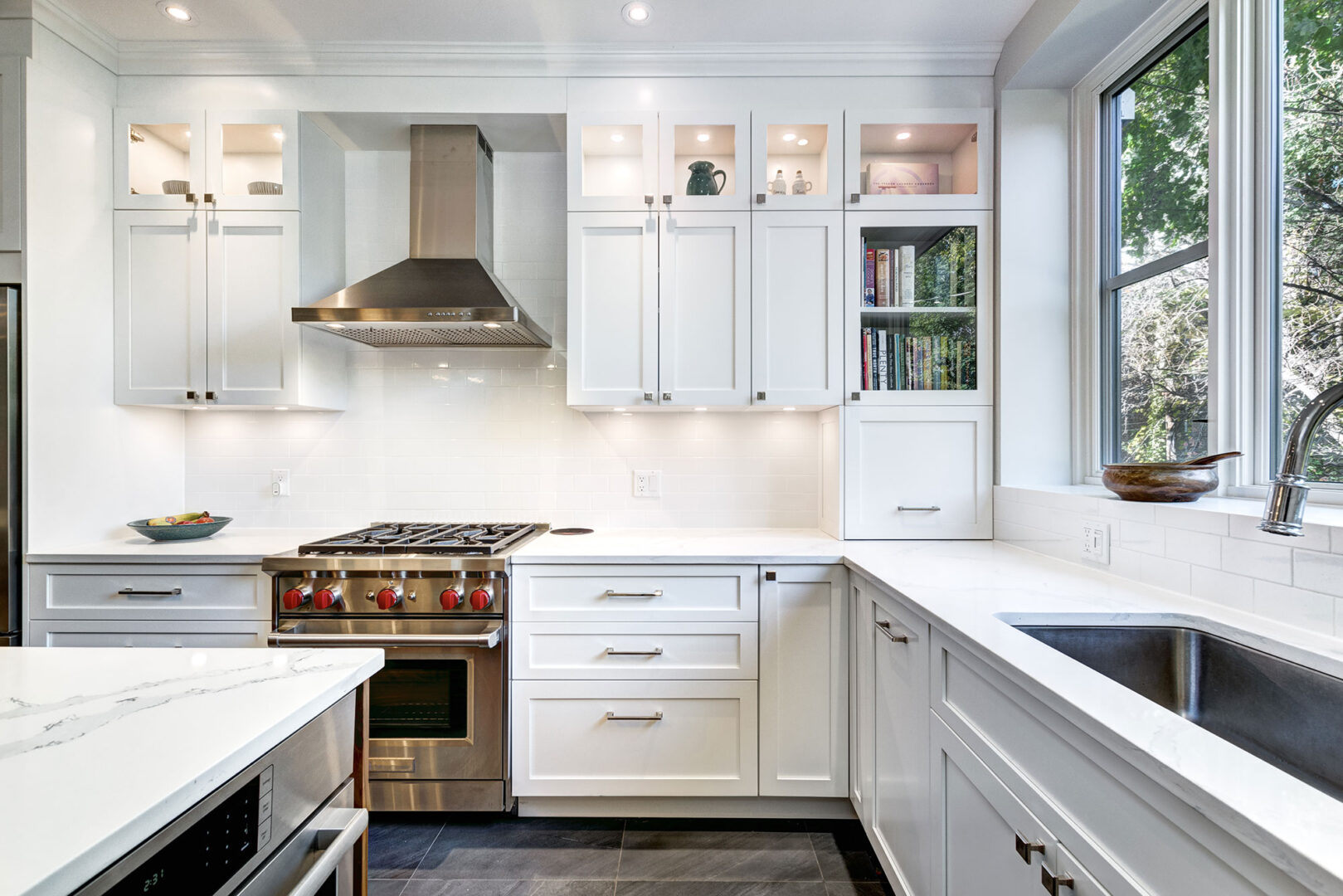 Modern white kitchen with stainless steel appliances, gas stove, and ample counter space.