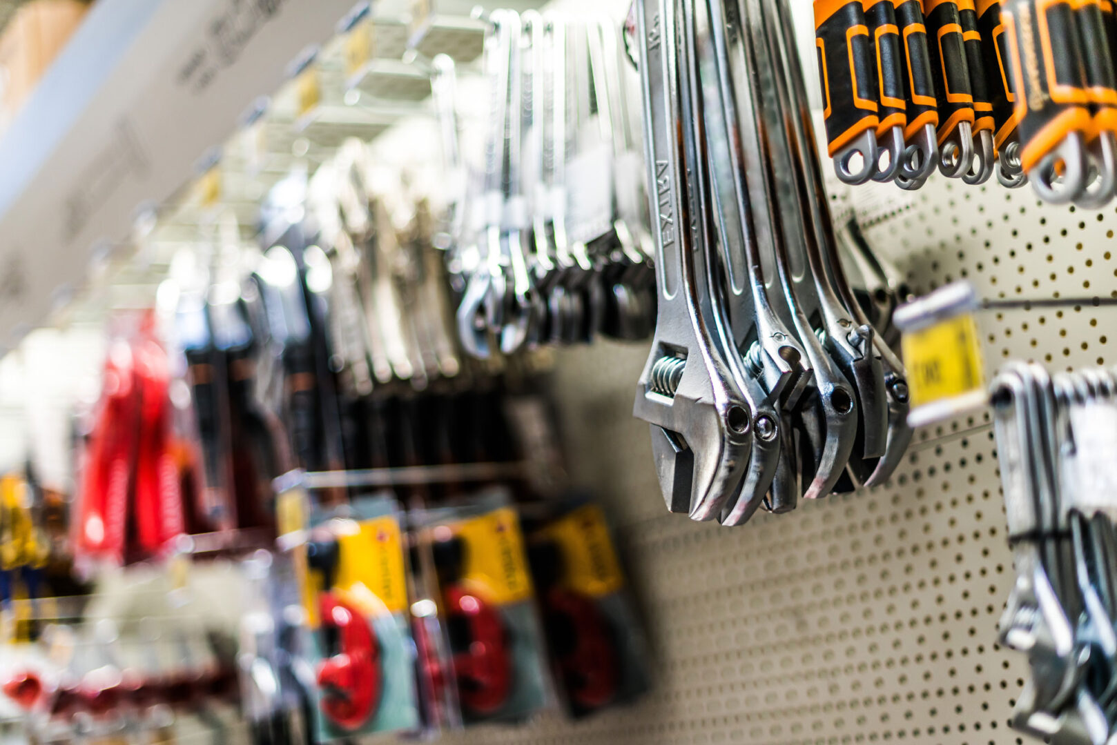 Wrenches hanging on a pegboard display in a hardware store aisle.