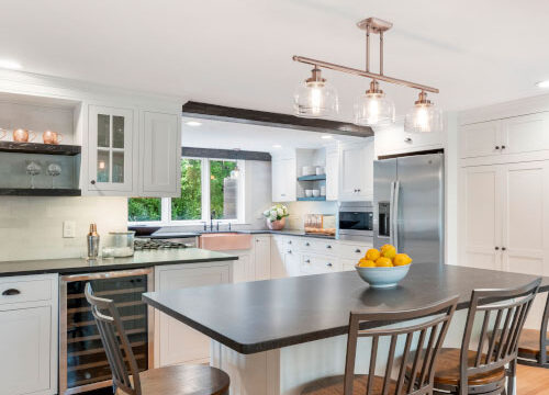 Modern kitchen with white cabinets, large island, pendant lighting, and stainless steel appliances.