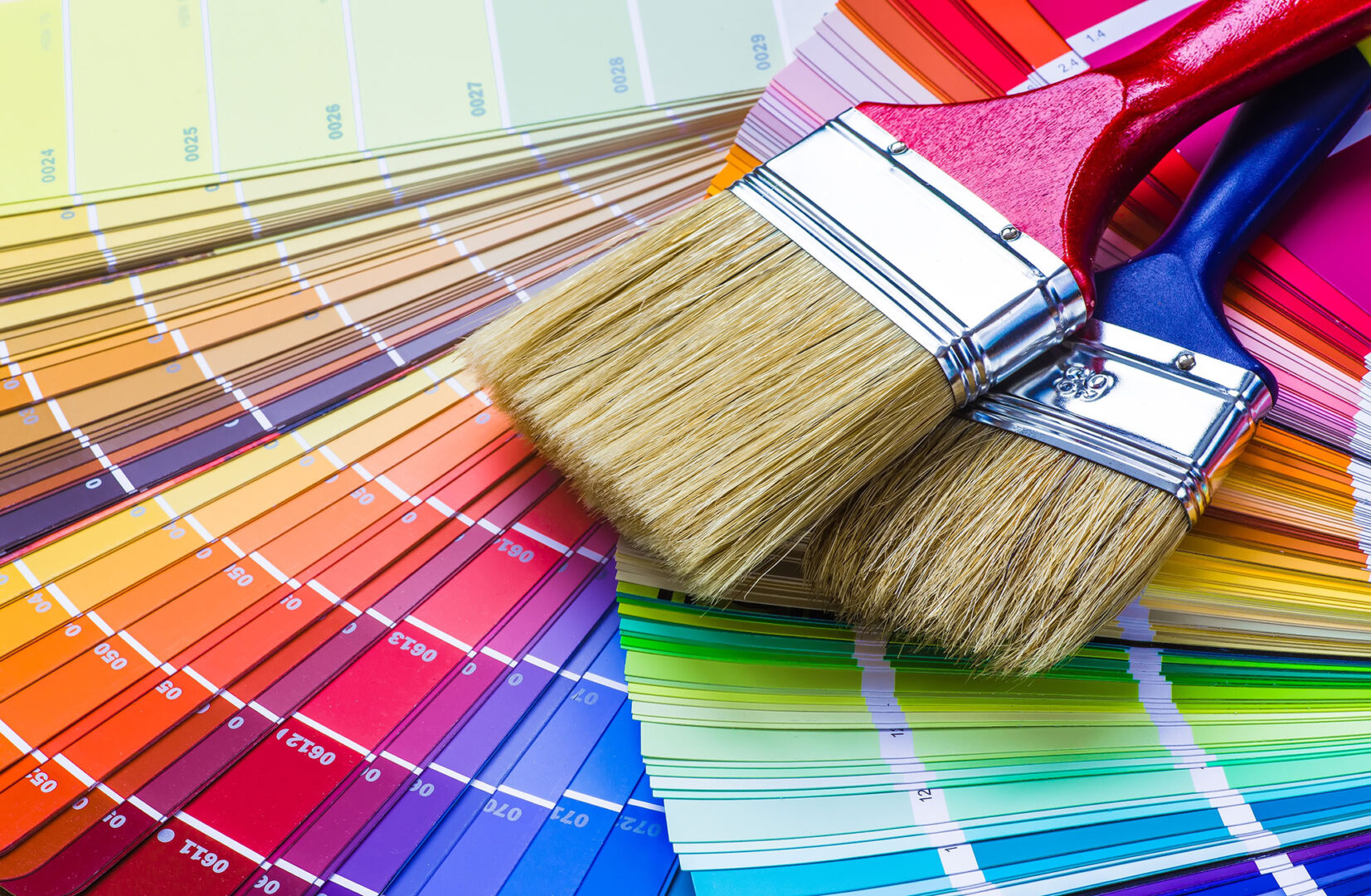Paintbrushes resting on a spread of colorful paint swatches.