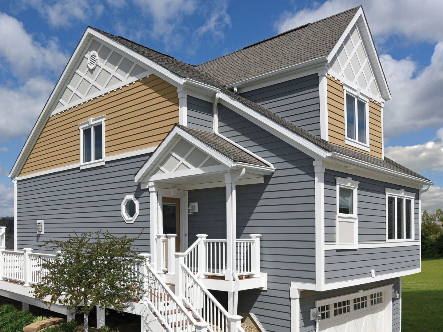 Two-story house with blue and beige siding, white trims, and a small front porch under a clear sky.