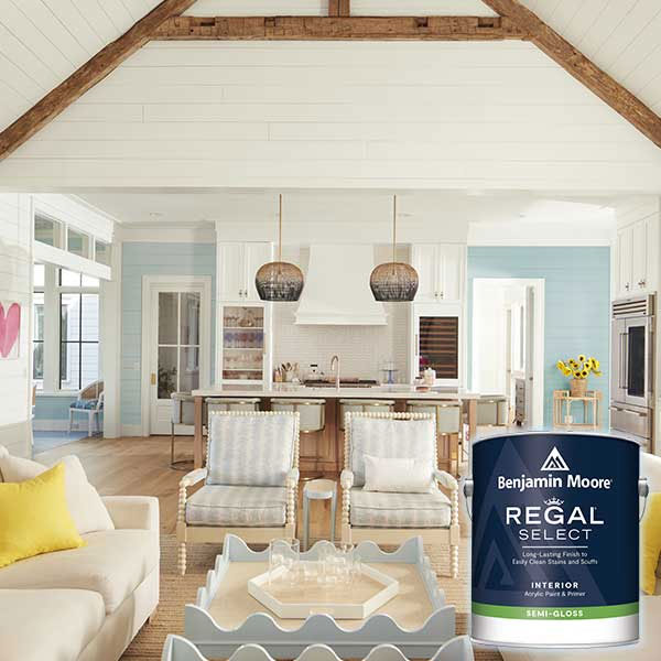 Bright living room with exposed beams, a cozy seating area, and a can of Benjamin Moore paint in the foreground.